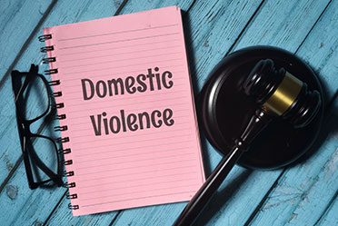 Gavel and notebook with "Domestic Violence" written on it.