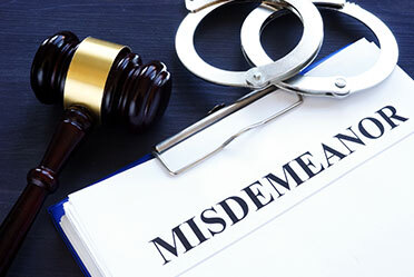 Gavel, handcuffs, and clipboard displaying 'Misdemeanor'