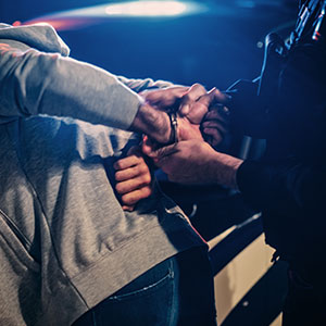 Law enforcement detaining a person during a nighttime arrest scene.