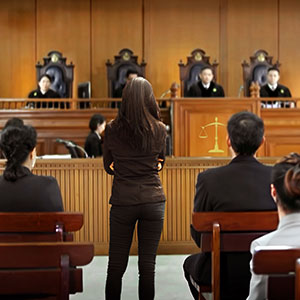 Legal proceedings in a courtroom with judges, attorneys, and attendees.