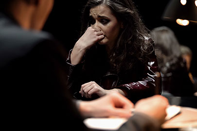 A distressed woman biting her nails while seated across from someone, representing family violence allegations.