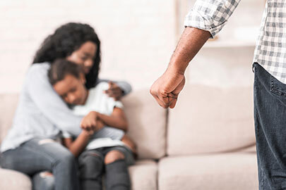 Woman hugging child while man makes a fist at them, Family Violence Charge.