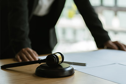 A legal professional stands near a gavel, documents, and pen, symbolizing legal consultation or judgment.