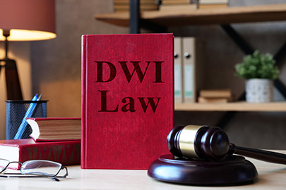 Red law book labeled DWI Law on a desk with a gavel, discussing passenger arrests in Texas