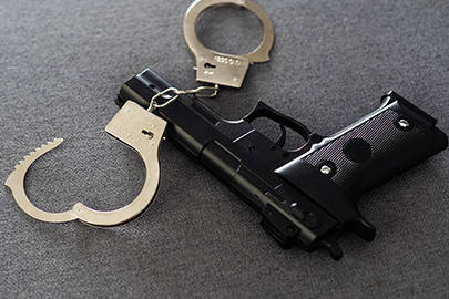A handgun and a pair of handcuffs on a dark surface, illustrating how a Family Violence Arrest Affects Your Gun Rights In Texas.