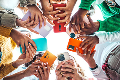 Group of people holding smartphones together in a circle, viewed from below.