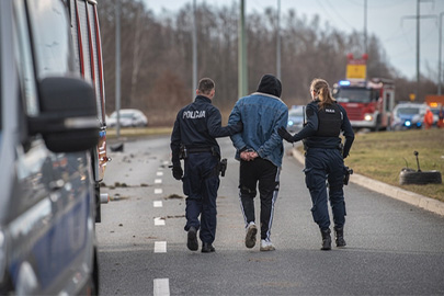 Police officers escorting a handcuffed individual on a Texas roadway.